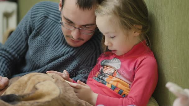 Pieni lapsi tyttö isän kanssa pelaa peliä matkapuhelimella pimeässä huoneessa , — kuvapankkivideo