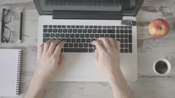 Um homem trabalhando em um laptop está bebendo café . — Vídeo de Stock