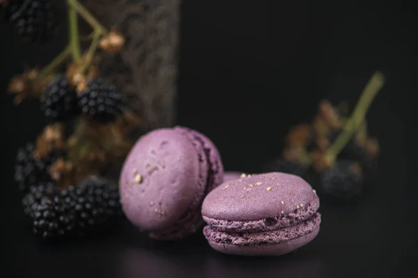 Macaroons doces com amoras pretas em bacground preto Fotos De Bancos De Imagens Sem Royalties