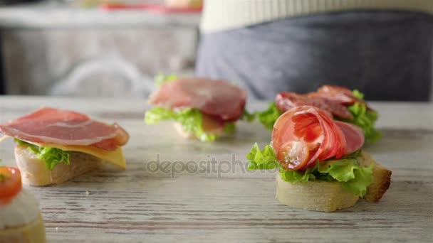 Donna che fa sandwich con foglia di insalata, diffusione, pomodorini ciliegia — Video Stock