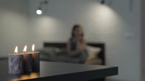 Menina triste na cama à luz de velas — Vídeo de Stock