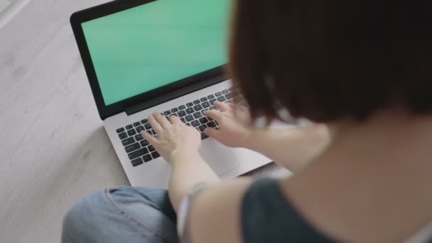 Молодая женщина сидит за ноутбуком крупным планом — стоковое видео
