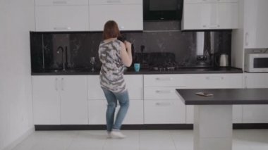 genç çekici kadın modern mutfağında dans.