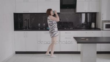 Mutfakta sabah pijama giymiş dans komik genç kadın.