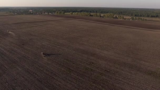 Vista aérea sobrevoando o topo de uma colheitadeira e trator em um campo — Vídeo de Stock