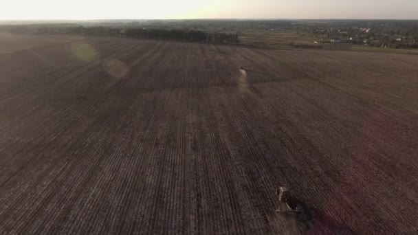 Aerial view flying over the top of a combine harvester and tractor in a field — Stock Video