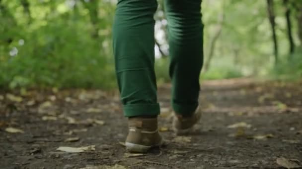 Ноги молодой девушки, которая уходит, зеленые джинсы и кроссовки — стоковое видео