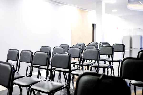 Black chairs stand in even rows in the classroom. Room for lectures. Without people — 图库照片