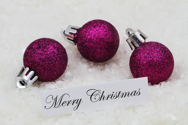 Feliz cartão de Natal com bugigangas roxas cobertas com brilho na superfície nevada — Fotografia de Stock