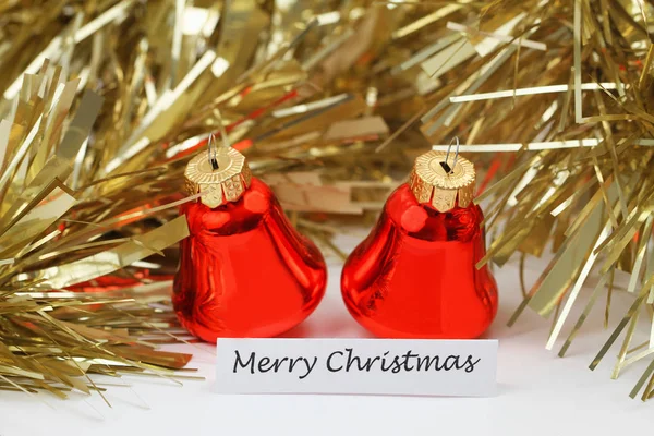 Feliz cartão de Natal com sinos vermelhos e corrente dourada cintilante — Fotografia de Stock