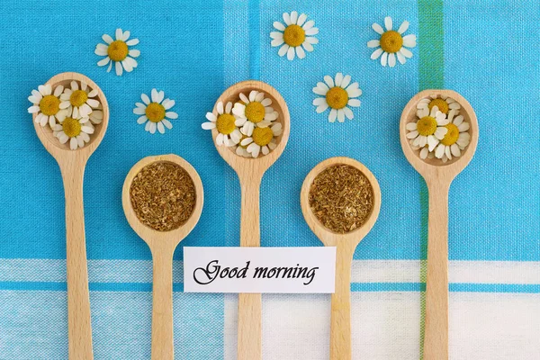 Carte du matin avec fleurs de camomille sur cuillères en bois sur tissu à carreaux — Photo