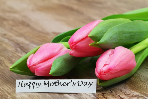 Šťastné matky den karty s růžové tulipány na dřevěný povrch — Stock fotografie