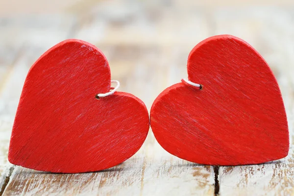 Dvě červené dřevěné srdce na dřevěné desce — Stock fotografie