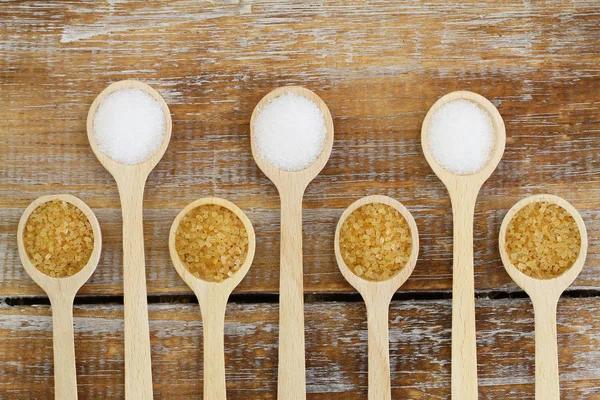 Tahta kaşıklar rustik ahşap yüzeyi üzerinde beyaz ve kahverengi şeker
