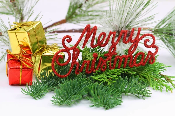 Feliz Navidad escrita con cartas cubiertas de purpurina roja sobre pino y regalos de Navidad en miniatura — Foto de Stock