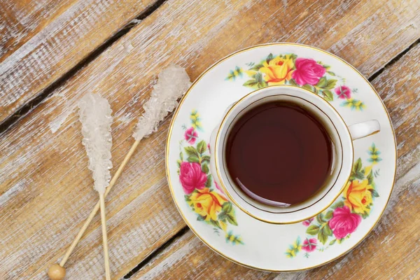 茶在老式杯子和糖棍子在木表面 — 图库照片