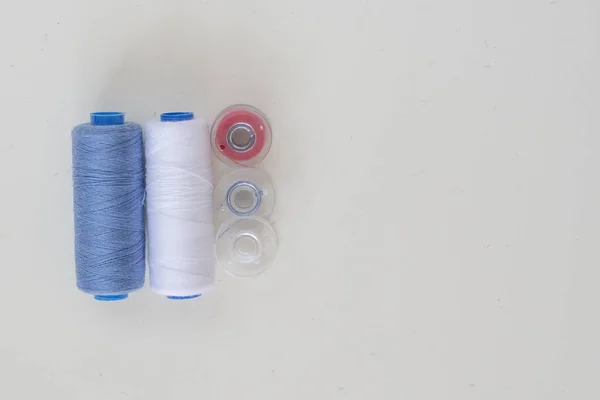 Bobinas coloreadas y carretes de hilo para coser a máquina sobre un fondo claro —  Fotos de Stock