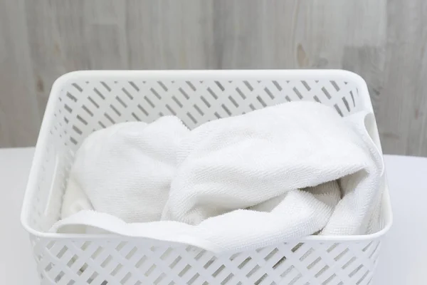 Fehér törölköző fehér műanyag szennyeskosárban, szürke háttérrel. A tisztaság, frissesség és érzékenység jele — Stock Fotó