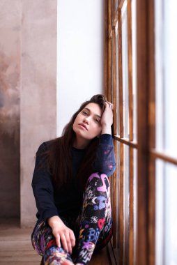 Sakin bir poz pencere üzerinde oturan güzel kız 