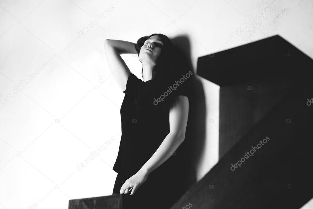 A young girl standing by the wall and posing dramatically. Black and white photo