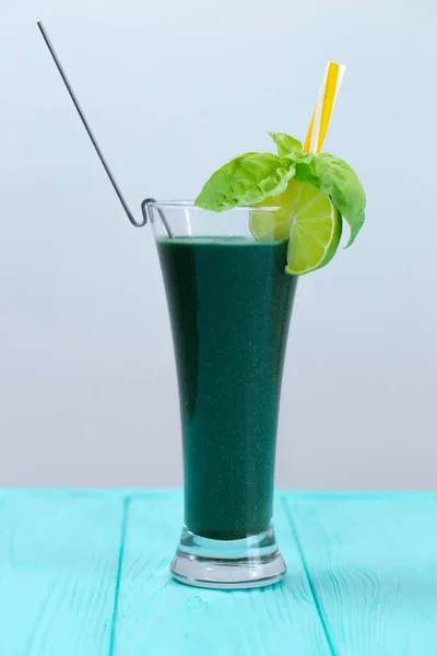 Natural vegetable cocktail with kiwi and other greens. A cocktail is decorated with lime, basil and yellow straw. A fresh drink for people who watch their health.