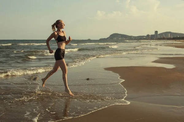 Mujer sonriente corriendo en la playa —  Fotos de Stock