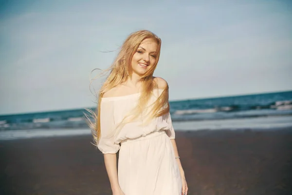 Blondýnka v bílých šatech na pláži — Stock fotografie
