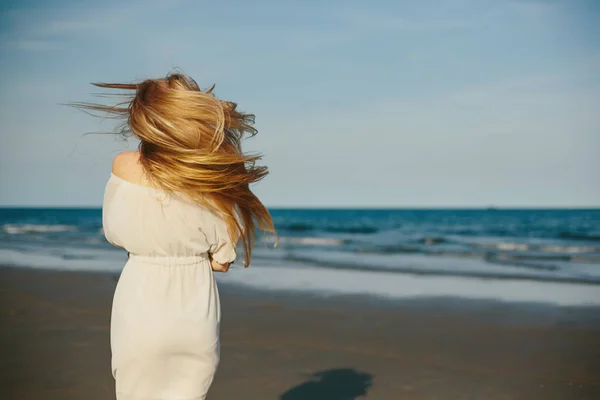 Femme blonde en robe blanche sur la plage — Photo