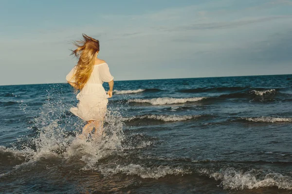 Mujer joven en vestido blanco corriendo en el mar —  Fotos de Stock