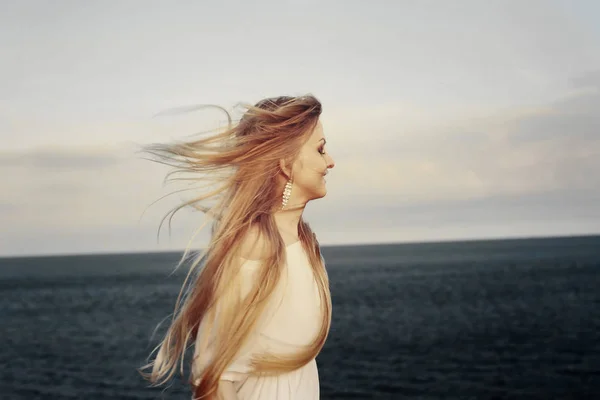 Žena v bílých šatech líbí Mořský vítr — Stock fotografie