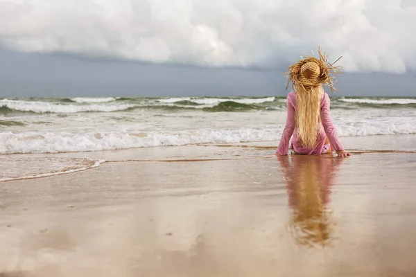 Blonde Frau sitzt am Meeresufer — Stockfoto