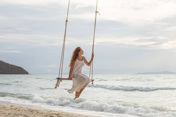 Femmina seduta sull'altalena sulla riva del mare — Foto Stock