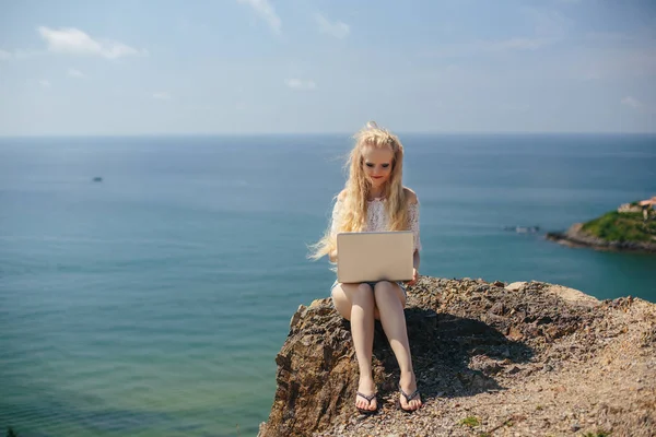 Женщина сидит на пляже с ноутбуком — стоковое фото