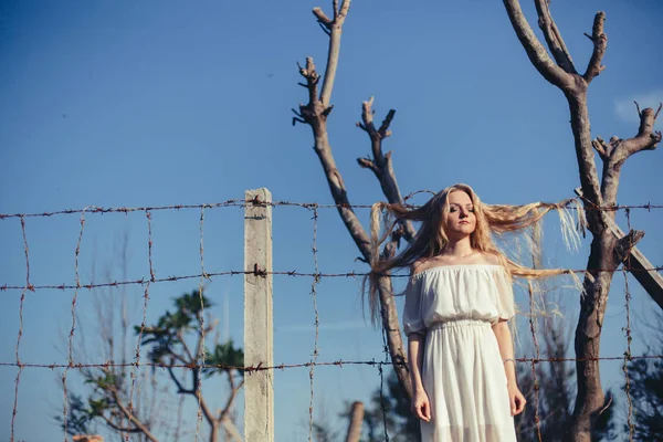 Beautiful woman staying with long hair on barbed wire — Stock Photo, Image