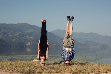 Couple of young yogis stand on head clipart