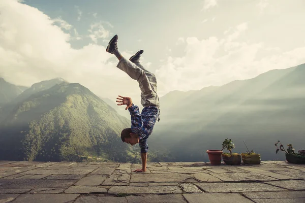 Young sporty man doing handstand in mountains — Stock Photo, Image