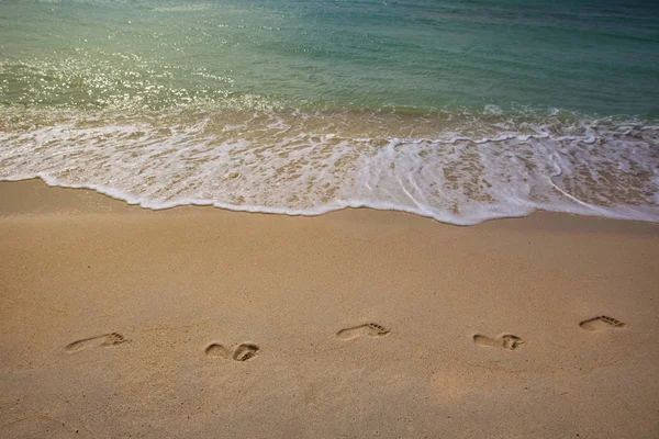 Wave and footsteps on beach — Stock Photo, Image