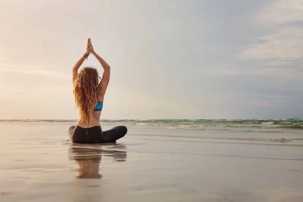 Женщина практикует йогу на берегу моря — стоковое фото