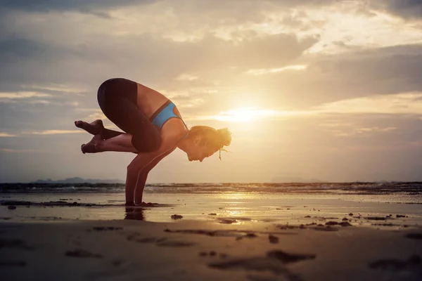 Junge Frau praktiziert Yoga am Strand bei Sonnenuntergang — Stockfoto