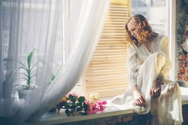 창가에 앉아 있는 젊은 여자 — 스톡 사진