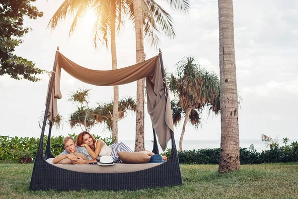 Jeune couple couché sous les palmiers — Photo