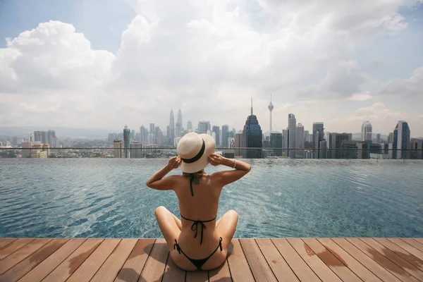 Mujer con sombrero blanco sentada en la piscina — Foto de Stock