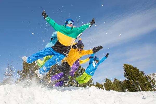 Amigos felizes pulando na neve — Fotografia de Stock