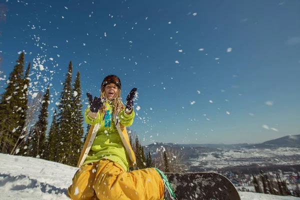 Vrouwelijke snowboarder spelen met sneeuw — Stockfoto