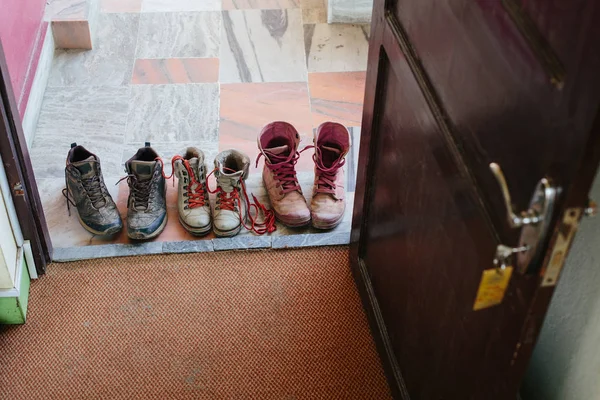 modern casual boots on the floor at hotel doorstep. Pink white and black color, dirty after long travel