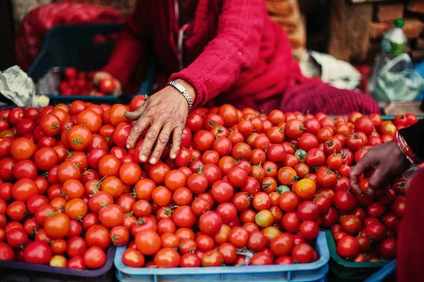 Fresh tomato on street asian market. Red coloured vegetable and seller clothes