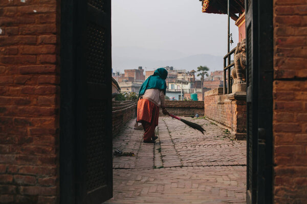 Woman clean small Temple area in old city Bhaktapur, Nepal