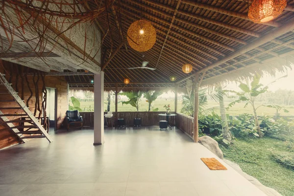 バリ島のヤシの木ジャングルの中に竹の屋根を持つ石の天然素材の家 — ストック写真