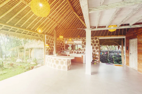 バリ島のヤシの木ジャングルの中に竹の屋根を持つ石の天然素材の家 — ストック写真