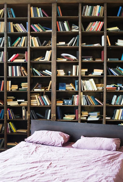 bookshelf with books and bed in bedroom